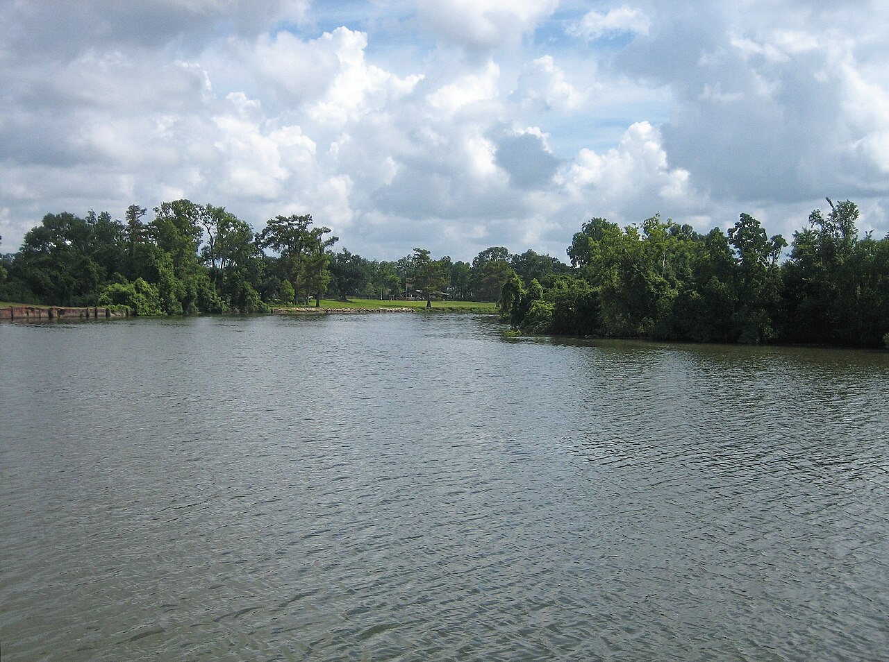 The wide Vermilion River at Abbeville, tree-lined banks under a cloudy sky.