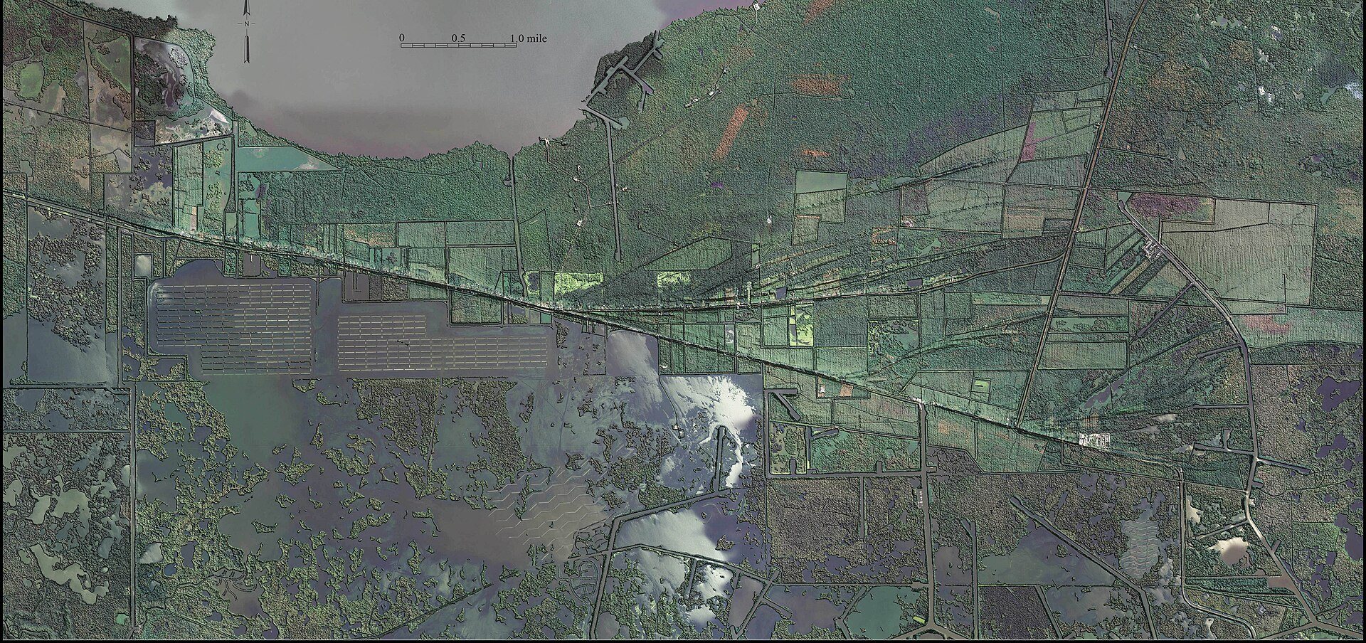Aerial map of Pecan Island, a long wooded ridge crossed by a highway, surrounded by marsh, ponds and open water.